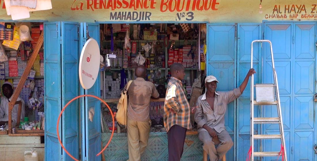 Des hommes devant une boutique dans PK 5, un quartier majoritairement musulman au sein de la capitale. La ville a été longtemps divisée entre chrétiens et musulmans depuis que les Anti-Balaka ont pris les armes contre les Seleka et les musulmans en décembre 2013. 15 septembre 2014 (VOA / Bagassi Koura).